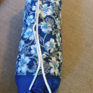 May include: A blue and white drawstring bag with a floral pattern. The bag is made of quilted fabric and has a white drawstring.