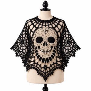 May include: A black and beige crochet poncho featuring a prominent skull design at the center. The garment is constructed with an intricate web-like pattern throughout, with black yarn forming the spiderweb structure and beige yarn for the skull.
