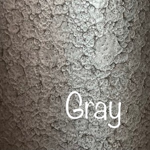 May include: Close-up of a textured, metallic surface with a gray color. The word "Gray" is written in white on the surface.