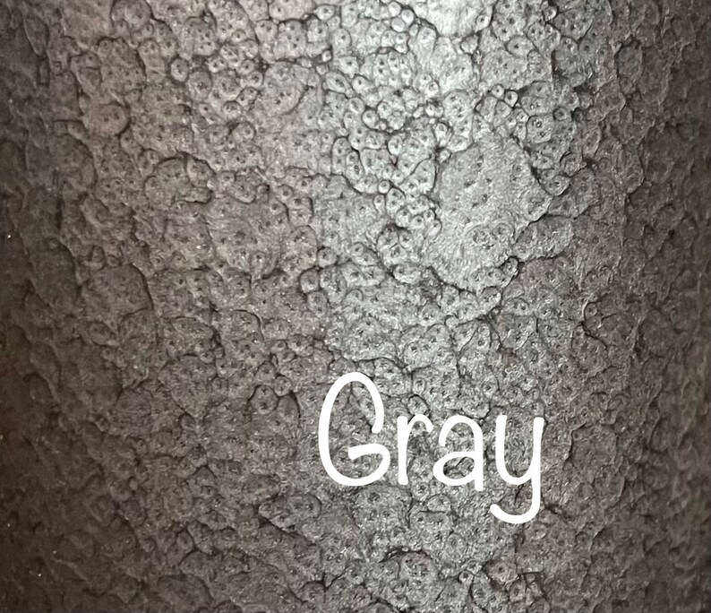 May include: Close-up of a textured, metallic surface with a gray color. The word "Gray" is written in white on the surface.