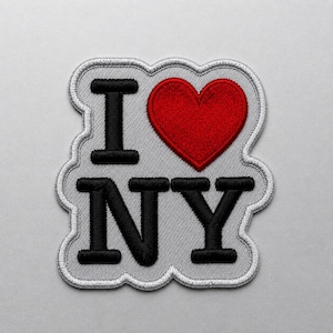 May include: A fabric patch featuring the embroidered text I heart NY, where the heart is a solid red shape and the letters I, N, and Y are black. The design is set against a light gray background with a white stitched border outline.