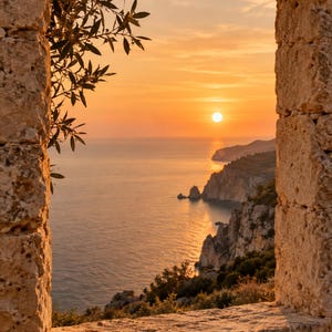 May include: A stone window frame with rough, textured edges overlooks a coastal landscape at sunset. The sun hangs low over the calm sea, casting a warm orange glow across the water and the rugged cliffs that extend into the horizon.