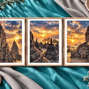 May include: A set of three framed wall art prints featuring stone temple structures at sunrise. Each print displays intricate architectural details of ancient monuments under a vibrant orange and blue sky with clouds, all enclosed in light wood frames.