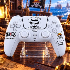 Op de afbeelding: Een witte draadloze gamecontroller met zwarte grafische prints. Het centrale touchpad toont een personage met een strooien hoed. De linkerkant bevat de tekst One Piece Going World en de rechterkant toont een schedel-logo met de tekst Marine.