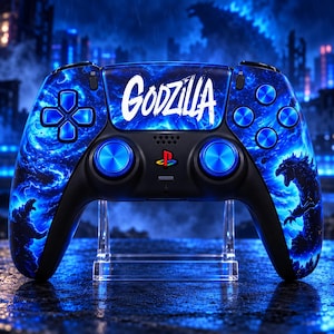Può includere: Un controller per videogiochi wireless caratterizzato da un motivo a energia vorticosa blu e nero con sagome di Godzilla. La parola GODZILLA è stampata in bianco sul touchpad centrale. Include levette analogiche e pulsanti blu metallizzato.