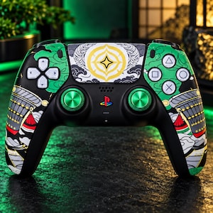 Könnte beinhalten: Ein schwarzer Videospiel-Controller mit einer individuellen Grafikschale in Grün, Weiß und Rot. Das mittlere Touchpad zeigt ein gelbes Sternemblem, während die beiden Analogsticks in Metallic-Grün gehalten sind. Ein mehrfarbiges PlayStation-Logo ist zu sehen.