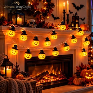 May include: A string of Halloween fairy lights featuring orange jack-o'-lanterns wearing black witch hats. Each pumpkin has a carved face and emits a warm glow. The lights are draped across a fireplace mantel decorated with autumn leaves.