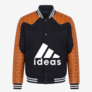 Könnte beinhalten: Eine schwarze Collegejacke mit hellbraunen Ärmeln, die ein sich wiederholendes braunes Monogrammmuster aufweisen. Auf der Vorderseite befindet sich eine große weiße Grafik mit drei diagonalen Streifen über dem kleingeschriebenen Wort ideas.