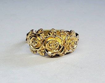 May include: A gold ring with three roses sculpted on the band.