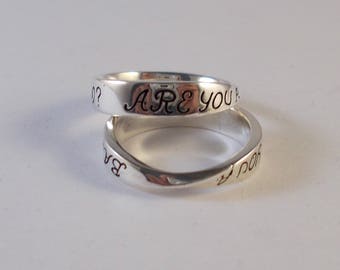May include: Two silver rings with the words "ARE YOU" and "ARE YOU" engraved on them.