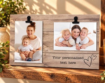 Op de afbeelding: Een rechthoekig houten fotodisplaybord met een lichtbruine houtnerfafwerking. Het is voorzien van twee zwarte metalen clips aan de bovenkant om foto's vast te houden. Het bord bevat de gedrukte tekst "Your personalized text here" en twee hartjes.