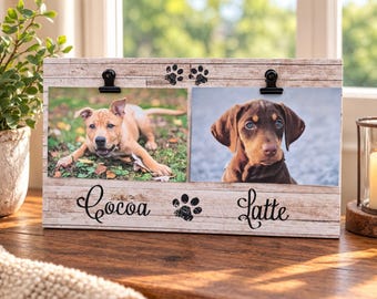May include: A rectangular wooden photo frame with a light brown faux-wood grain finish. It features two black metal clips at the top for holding photos. The frame displays the black script text "Cocoa" and "Latte" with two black paw print icons.
