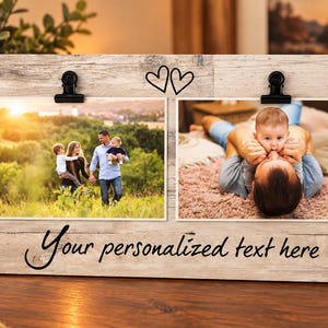 May include: A rectangular wooden photo frame with a light-colored, weathered wood grain finish. It features two black metal clips for holding photos and a decorative outline of two hearts. The text "Your personalized text here" is printed in black.