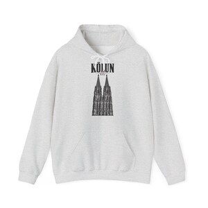 Op de afbeelding: Een lichtgrijze gemêleerde hoodie met een zwarte grafische print van de Dom van Keulen op de borst. Boven de illustratie van de kathedraal staat de tekst KÖLÜN in een vet, donker lettertype, met het woord Köln in kleinere letters eronder.
