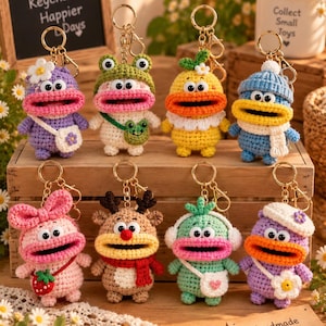 May include: Eight crocheted animal keychains with wide open mouths, each featuring unique accessories like hats, scarves, and small bags. The colorful figures include a purple creature with a flower, a frog-themed character, and a reindeer-inspired design.