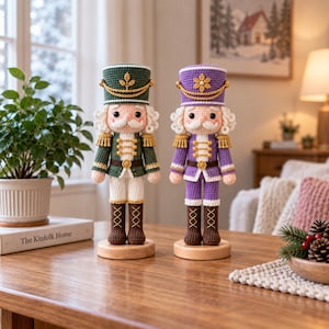 Puede incluir: Dos figuras de cascanueces tejidas a ganchillo sobre bases de madera. Una figura viste un uniforme verde oscuro con detalles dorados, mientras que la otra viste un uniforme morado con detalles dorados. Ambas tienen pelo blanco, bigote y sombreros.