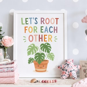 Może przedstawiać: Biała oprawiona grafika ścienna z napisem LET'S ROOT FOR EACH OTHER kolorowymi literami nad zieloną rośliną monstera w terakotowej doniczce z uśmiechniętą buźką. Wzór jest wyśrodkowany na białym tle wewnątrz ramki.