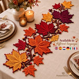 May include: A crochet table runner featuring a series of interconnected maple leaves in shades of red, orange, and yellow. The design includes small crocheted acorns and stems, creating a continuous vine-like pattern across the center of the table.