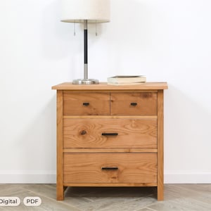 May include: A wooden nightstand featuring a natural light brown wood grain finish, two small top drawers, and two larger bottom drawers. Each drawer is equipped with a thin, horizontal black metal handle. A table lamp sits on the top surface.