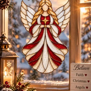 May include: A stained glass angel ornament featuring white and red panels with gold outlines, suspended by a gold ribbon. The angel has outstretched wings and holds a gold star. A sign nearby reads Believe, Faith, Christmas, Angels, Brighter Days.