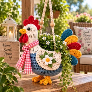 Peut inclure: Une jardinière en crochet en forme de poule avec une tête crème, une crête et des barbillons rouges, un bec jaune et un corps bleu. Elle porte une écharpe à carreaux rouges et blancs et une queue multicolore. Une fleur blanche est fixée sur le côté.
