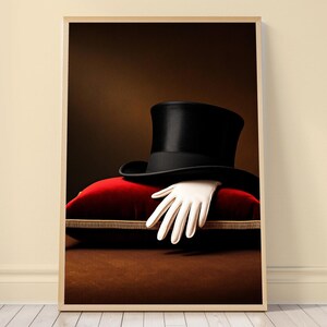 Può includere: Un cilindro nero poggiato su un cuscino di velluto rosso con finiture dorate. Un singolo guanto bianco è posizionato sotto la tesa del cappello, con le dita che ricadono sul bordo anteriore del cuscino rosso, creando un'esposizione formale.