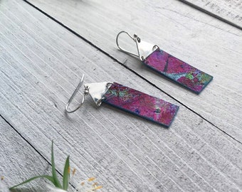 May include: A pair of silver earrings with rectangular pink and blue patterned metal accents.