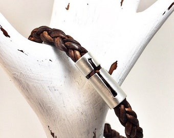 May include: A brown leather braided bracelet with a silver cross charm.