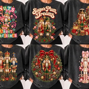May include: A collection of six charcoal grey crewneck sweatshirts, each featuring a distinct Christmas-themed graphic print. Designs include nutcrackers, a decorated tree, a wreath, and text such as NUTS ABOUT CHRISTMAS and Sugar Plum Dreams.