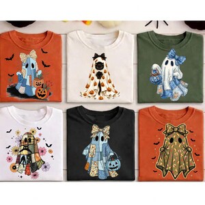 Op de afbeelding: Zes t-shirts met Halloween-thema afbeeldingen van geesten en katten. De ontwerpen bevatten geesten met strikken, patchworkpatronen, bloemenaccenten en luipaardprint, samen met een zwarte kat onder een laken met pompoenen op diverse kleuren shirts.