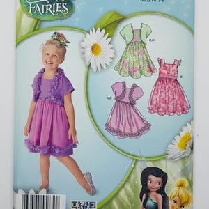 May include: Simplicity Disney Fairies sewing pattern featuring a young girl in a purple dress with a matching jacket. The pattern includes illustrations of different dress designs and Disney Fairies characters. The size is US 3,4,5,6,7,8.