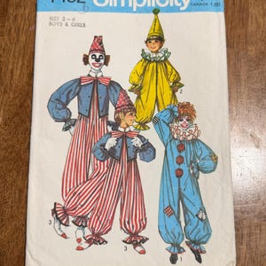 May include: A Simplicity 7162 sewing pattern envelope for children's clown costumes in sizes 2-4. The cover features illustrations of three different clown outfits: a red and white striped jumpsuit, a yellow jumpsuit with a cone hat, and a blue jumpsuit.