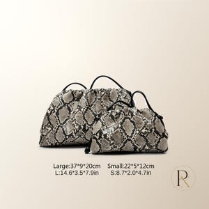 May include: Two gathered pouches with a snakeskin pattern in shades of gray, black, and white. The large pouch measures 14.6 by 3.5 by 7.9 inches, and the small pouch measures 8.7 by 2.0 by 4.7 inches. Both feature black handles and drawstring closures.