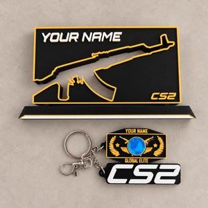 Puede incluir: Un soporte rectangular negro y amarillo con el texto YOUR NAME y CS2 y la silueta de un rifle, junto a un llavero con un emblema de globo terráqueo azul, el texto YOUR NAME, GLOBAL ELITE y el logotipo CS2.