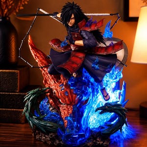 May include: A detailed anime character figurine featuring a dark-haired warrior in red and black samurai-style armor. The figure is posed dynamically amidst swirling translucent blue energy flames and a large, textured orange dragon head.