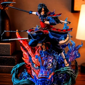 May include: A detailed anime-style figurine of a character with long black hair, wearing red and blue armor, holding a scythe. The character stands atop a large, translucent blue and red dragon-like creature with glowing red eyes and flames.