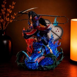 May include: A detailed anime character figurine featuring a dark-haired warrior in red and blue armor, wielding a large scythe and a circular fan with red markings. The figure stands atop a translucent blue dragon head surrounded by blue flames.