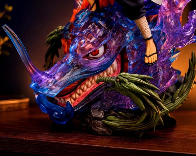 May include: A detailed anime-style figurine featuring a translucent blue and purple dragon head with a sharp horn and visible teeth. A human foot wearing a black sandal rests on the dragon, which is accented by green textured elements.