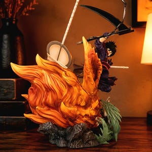 May include: A dynamic anime-style figurine featuring a character with dark hair in a purple outfit, wielding a large black scythe. The figure is surrounded by sculpted orange flames and green foliage, set upon a textured gray rocky base.