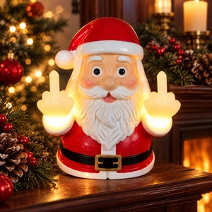 May include: A ceramic Santa Claus figurine with a glossy red hat and suit, a white beard, and a black belt with a gold buckle. The Santa figure is illuminated from within and is depicted with both hands raised, each showing a middle finger gesture.