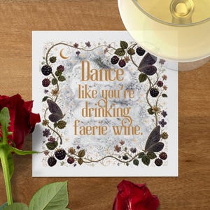 May include: A square coaster featuring the gold text Dance like you're drinking faerie wine. The design includes a border of dark purple butterflies, black blackberries, green leaves, and small flowers on a white background with a crescent moon.