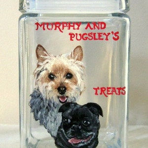 Puede incluir: Un tarro de vidrio transparente con tapa blanca, que presenta un retrato pintado a mano de dos perros. El Yorkshire Terrier está a la izquierda, y el Pug está a la derecha. El tarro está etiquetado como "Murphy and Pugsley's Treats".