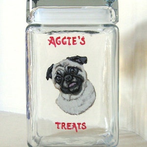 May include: A clear glass jar with a white lid, featuring a hand-painted image of a pug dog. The jar is labelled "Aggie's Treats" in red lettering.