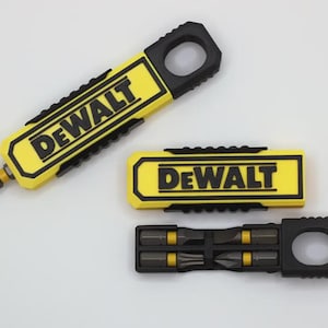 May include: Three DeWalt branded tool accessories featuring a yellow and black colour scheme. One piece holds a single screwdriver bit, another is a rectangular yellow case with the DeWalt logo, and the third is a black holder with four bits.