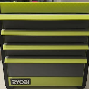 May include: A lime green and dark grey tool chest featuring four horizontal drawers with matching lime green handles. The unit has a black frame and the brand name RYOBI is printed in white letters on a black rectangular label at the bottom.