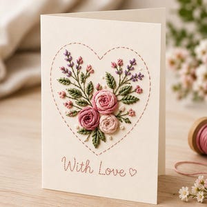 May include: A cream-coloured greeting card featuring a heart-shaped outline stitched in pink thread. Inside the heart is an embroidered floral arrangement of pink roses, green leaves, and purple sprigs. The text "With Love" is stitched in pink below.