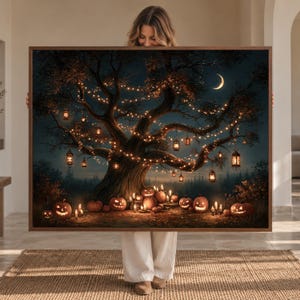 May include: A rectangular framed wall art print featuring a large, dark tree at night illuminated by glowing string lights and hanging lanterns. The base of the tree is surrounded by numerous carved jack-o'-lanterns and lit candles under a crescent moon.