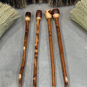 Puede incluir: Cuatro bastones de madera con vetas naturales y acabado barnizado. Las puntas son redondeadas y de color madera más claro. Los bastones son marrones con detalles de madera más claros.