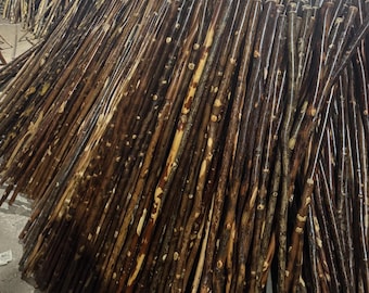 May include: A large pile of wooden walking sticks. The sticks are various shades of brown, with lighter, natural wood tones interspersed. The sticks appear to be made from natural branches, with knots and textured surfaces visible. The sticks are stacked together.