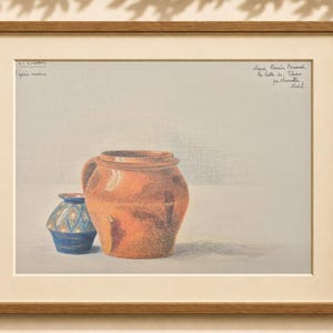 Peut inclure: Un dessin encadré représentant deux récipients en céramique. Un grand pot arrondi de couleur orange-brun est placé à côté d'un vase plus petit à motifs bleus. L'œuvre comporte du texte manuscrit dans les coins supérieurs, sous passe-partout.